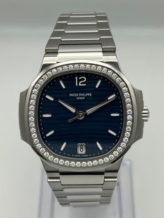 The Patek Philippe Ladies Nautilus features a round octagonal shape diamond-set bezel and 35.2mm stainless steel construction. The watch has a blue embossed dial with gold applied numerals and hour markers with dual timezones for local and home time indication. It is finished with a stainless steel bracelet and fold-over clasp endowed with a new adjustment system, providing the wearer with between 2 and 4 mm of extra bracelet length for increased comfort. Reference Number 7118/1200A-001 Model Na Comfort Reference, Patek Watches, Gold Statement Jewelry, Fall Rings, Blue Cases, Patek Philippe Nautilus, Breitling Navitimer, Rolex Day Date, Bespoke Jewellery