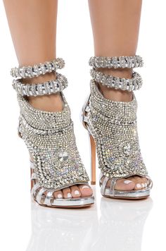 Feeling lucky? The Azalea Wang Push Your Luck Stiletto Sandal In Silver features a metallic faux leather upper, a large rhinestone and gem-detailed centerpiece with cushioned backing, exposed side cut outs, an ankle height shaft, cushioned ankle straps, a pointed peep toe, a stiletto heel, and a back ankle zipper closure. Pair this blinged out sandal with a bodycon mini and silver jewelry for a complete look. (All measurements approximate from size 7.5): - Peep toe - Stiletto heel - PU upper - 5.75” shaft height - 5.25” heel height - Imported Product ID: 317991 Dress Mules, Women High Heels, Rhinestone High Heels, Modern Sandals, Mule Shoes, Rhinestone Heels, Embellished Sandals, Stiletto Sandals, Silver Shoes