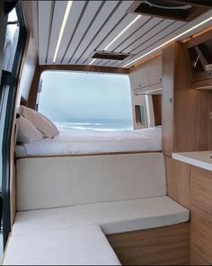 the interior of a motor home with a bed and sink in front of an ocean view