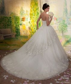 a woman in a wedding dress is standing near a wall with flowers and petals on it