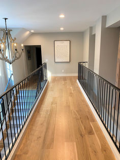 an empty room with wooden floors and black railings on the second floor is shown