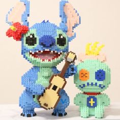 two toy figurines made out of legos, one is holding a guitar