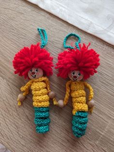 two crocheted dolls with red hair and green pants are sitting on a table