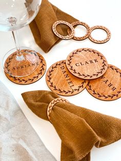 wooden coasters with personalized names on them sitting next to a glass of wine