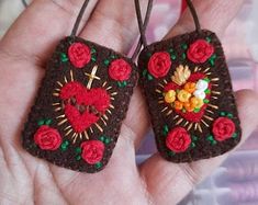 two small crocheted tags with roses on them are held in someone's hand