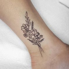 a small flower tattoo on the ankle that is black and white, with flowers growing out of it