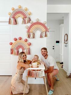 a man and woman sitting next to a baby in a highchair eating cake