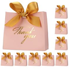 a pink gift bag with gold ribbon and thank you written on the front, along with six small tags