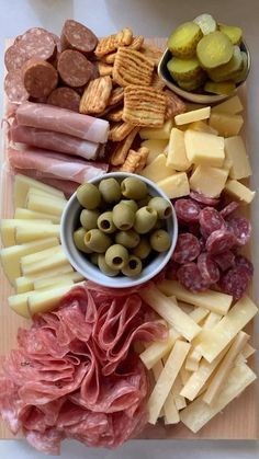 an assortment of cheeses, meats, and olives on a cutting board