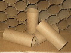 several rolls of toilet paper sitting on top of a cardboard box filled with empty cups