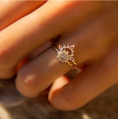 a woman's hand holding a ring with three small diamonds on the middle of it