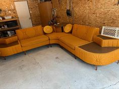 an orange couch sitting in a room next to a wooden wall