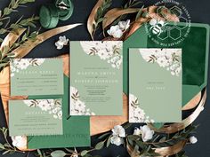 wedding stationery with green and white florals on the front, along with greenery