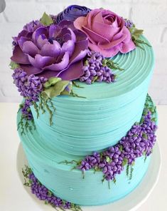 there is a blue cake with purple flowers on it