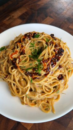 a white plate topped with pasta covered in sauce and parmesan cheese on top of a wooden table