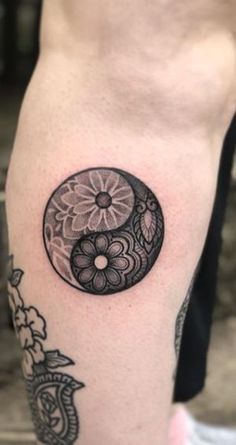 a black and white tattoo on the leg of a person with a flower in it