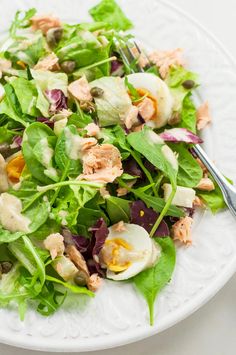 a white plate topped with salad and an egg