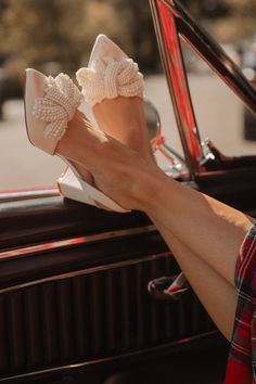 a woman's feet sticking out of the side window of a car with bows on them