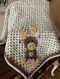 a crocheted blanket with a deer on it sitting on top of a dresser