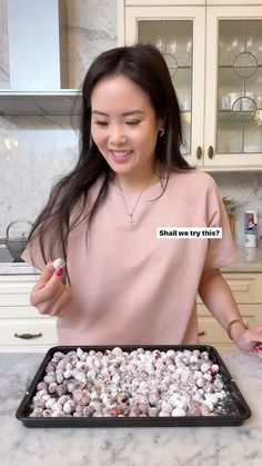 a woman standing in front of a baking pan filled with cookies and marshmallows