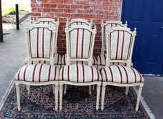 four chairs sitting on top of a rug next to a brick wall in front of a blue door