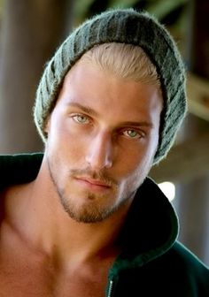 a shirtless man wearing a knitted hat and looking at the camera with an intense look on his face