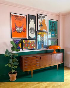 a living room with posters on the wall and a wooden dresser in front of it