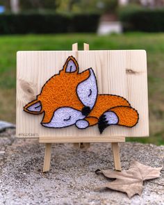 a small wooden easel with an image of a sleeping fox on it's side