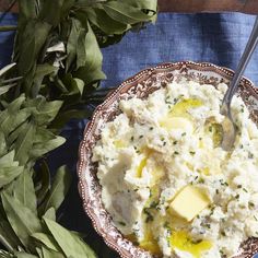 a bowl of mashed potatoes and butter on a blue tablecloth with green leaves