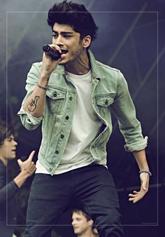 a man with a flower in his hair singing into a microphone