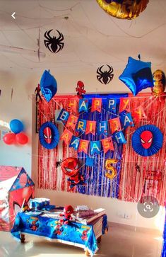 spiderman themed birthday party with balloons and streamers hanging from the ceiling, on a bed