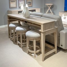 a table with four stools in front of it and a vase on the end