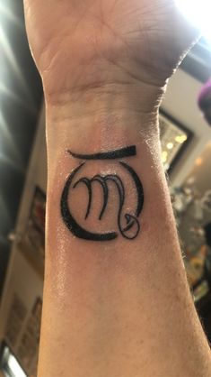 a wrist tattoo with the letter m on it