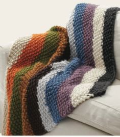 a crocheted blanket sitting on top of a white couch