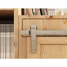 a close up of a door handle on a wooden cabinet with bookshelves in the background