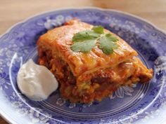 a blue plate topped with lasagna and sour cream