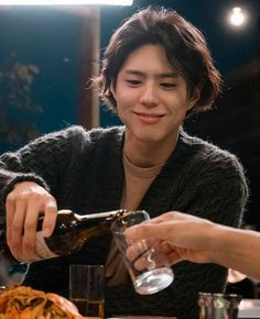 a person pouring something into a glass at a table