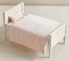 a small white bed with pink sheets and pillows