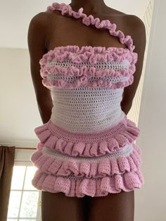 a mannequin wearing a pink and white crochet dress with ruffles