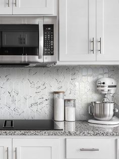 a kitchen with white cupboards and stainless steel appliances on the counter top, including a mixer