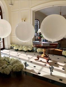 two large white balloons sitting on top of a table next to flowers and vases