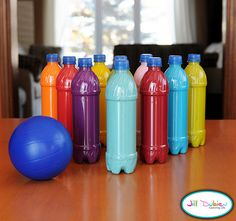 there are many different colored plastic bottles next to a blue ball on the wooden table