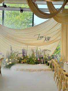 an indoor wedding setup with white draping and flowers