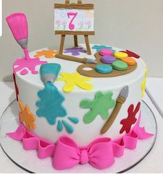 a birthday cake decorated with an artist's palette and pink bow