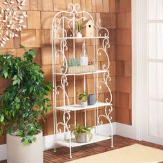 a white shelf with potted plants on it in front of a wooden paneled wall