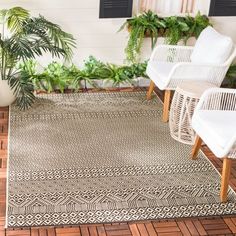 an outdoor area rug with chairs and potted plants