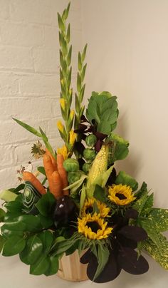 a basket filled with lots of different types of flowers and plants next to a brick wall