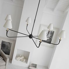 a chandelier hanging from the ceiling in a room with white walls and furniture