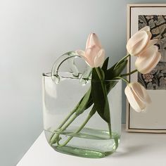 there is a vase with flowers in it on the table next to a framed photo