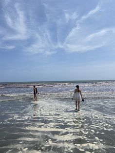 two people standing in the water at the beach